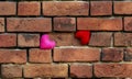 Two knit hearts red and pink are standing on a crumbling old red