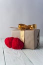 Two knitted hearts, gift box on rustic background