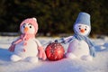 Two knitted snowmen stand under the bright winter sun in the snow. Between them lies a Christmas tree ball Royalty Free Stock Photo