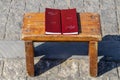 Two korans sitting on a grungy wooden table on cobblestone surface in sun with shadow