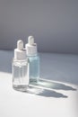 Two laconic bottles of cosmetic liquid in the rays of the harsh sun. Royalty Free Stock Photo