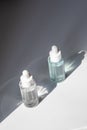 Two laconic bottles of cosmetic liquid in the rays of the harsh sun. Royalty Free Stock Photo