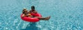 Two ladies in bikini are joyfully floating together on a big inflatable ring in blue water