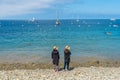 Two ladies on the rocky beach looking at the ocean view and horizon