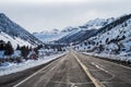 Two lane paved road ascending into snowy mountains