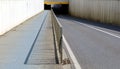 Two lane road with a pedestrian and cycle path next to it separated by a railing. An underpass in front and high concrete walls