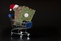 Two laptop hard drives and a red santa claus hat in a blue shopping basket. Black background. Christmas sale and discount concept Royalty Free Stock Photo