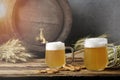 Two large beers in glass with wooden barrel on the wood background. Weizen beer