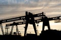 two large bridge cranes on the background of the sky at sunset. Outline of a girder crane on a cloud background. overhead cranes