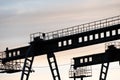 two large bridge cranes on the background of the sky at sunset. Outline of a girder crane on a cloud background. overhead cranes