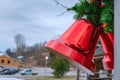 Two large Christmas red bells with red bow and pine leaves, street Christmas decoration, right side close up view, blurry Royalty Free Stock Photo