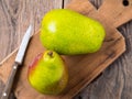 Two large fresh green pears and knife on a cutting Board on a wooden table. Royalty Free Stock Photo