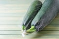 Two large green zucchini in a mesh bag. Wooden background. Copy space