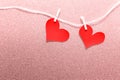 Two large hearts pinned to a rope on pink backgound