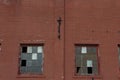 Two large industrial windows with broken frames in a red brick facade Royalty Free Stock Photo