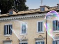 Two large iridescent soap bubbles against the facade of a building, Rome, Italy