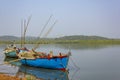 Two large old fishing boats with motors and fishing rods anchored off the coast against the backdrop of a river and green forest Royalty Free Stock Photo