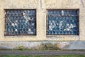 Two large old windows of an abandoned factory. Lattice on the broken windows.