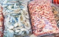 Two large plastic bags of frozen raw and cooked shrimp, on the counter of the fish market