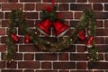 Green garland with red bells on a brick wall Royalty Free Stock Photo