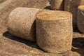 Two large rolls of yellow straw on farmland, close-up