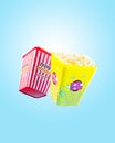 Two large servings of fresh, hot, buttered and caramel popcorn on a bright blue background. Movie night concept poster banner