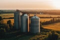 three silos in a field of crops at sunset