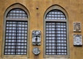 Two large windows with large grates and four stone coats of arms on the wall overlooking the park, of Villa Stibbert in Florence. Royalty Free Stock Photo