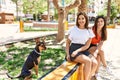 Two latin girls smiling happy sitting on bench with dog at the city Royalty Free Stock Photo