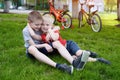 Two laughing boys having fun on the grass. Bicycles in the background Royalty Free Stock Photo