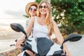 Two laughing girlfreinds motorbike travelers portrait behind the sunset sea coast Royalty Free Stock Photo