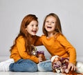 Two laughing kid girls friends in similar clothes sit on floor in kindergarten playing with their dolls Royalty Free Stock Photo