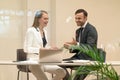 Two laughing project managers discuss updates while having a coffee break. Young business people in the suits with Royalty Free Stock Photo