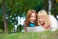 Two laughing sisters with laptop in the park Royalty Free Stock Photo