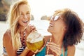 Two laughing women drinking from coconuts on a tropical beach Royalty Free Stock Photo