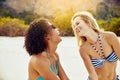 Young women in bikinis laughing together on a sandy beach Royalty Free Stock Photo