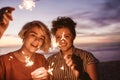 Two friends playing with sparklers on the beach at dusk Royalty Free Stock Photo