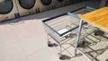 Two laundry basket trolley and table on tile floor with row of vending washing machines and clothes dryer in laundromat shop Royalty Free Stock Photo