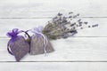 Lavender sachets and a bunch of dried lavender flowers on a white wooden planks background