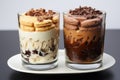 Two layered parfait desserts with chocolate and cookies in clear glasses