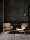 Two leather lounge chairs in a dark and darkened room, in the style of light gray and light brown, the helsinki school, neo-