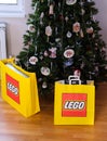 Two Lego paper bags with a Lego sets in it near a Christmas tree decorating with handmade Christmas ornaments