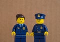 Two Lego police officers against brown background