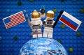 Two Lego spaceman minifigures with American and Russian flags stay on planet