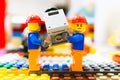 Two Lego toys of construction workers carrying a safe together