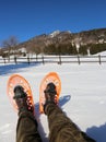 Two legs with corduroy pants and orange snowshoes in winter