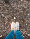 Two legs in white sneakers on a background of a camomile flower, protect the environment, standing on green grass Royalty Free Stock Photo