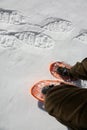 Legs of a young man that walks with orange snowshoes in winter