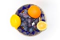 Two lemons, orange and plums on a plate Royalty Free Stock Photo