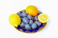 Two lemons, orange and plums on a plate Royalty Free Stock Photo